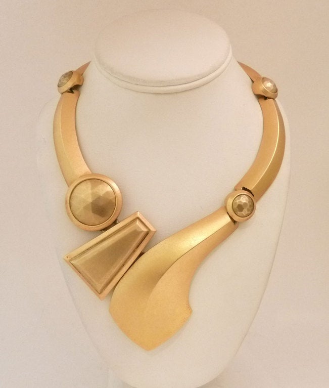 This is an impressive, large, dramatic necklace.  This vintage signed Monet necklace features a swirling geometric design in a gold-tone setting.  This necklace measures 16 ½? including a 1? extension with fold-over closure and the front is 2 ¾?