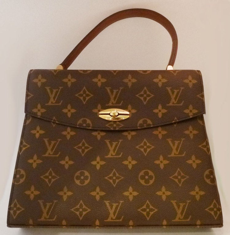 This vintage signed Louis Vuitton purse features the famous LV pattern logo.  This brown & gold leather purse with gold-tone accents measures 10 ¼? wide at the bottom and tappers up to 9 ¼? wide; the height is 8 ½? and the strap is 4 ½? up from