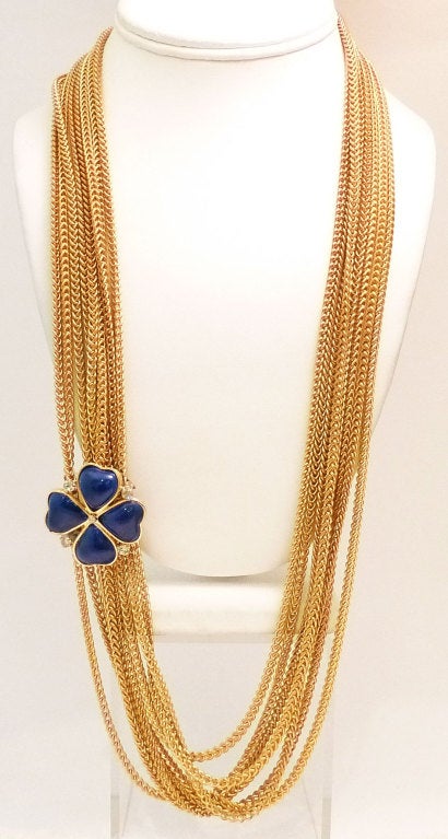 This vintage signed Chanel necklace features a multi-strand slide with gripoix glass and clear rhinestone accents in a gold-tone setting.   The sliding clover can be placed anywhere on the multi-chain necklace and measures 1 ¼ inches. A single link