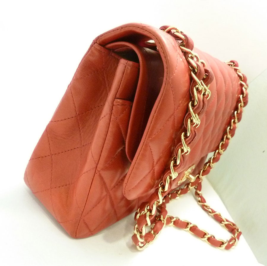 This vintage signed Chanel purse features the famous quilted double-flap design in a red leather with gold-tone accents. This purse measures 10