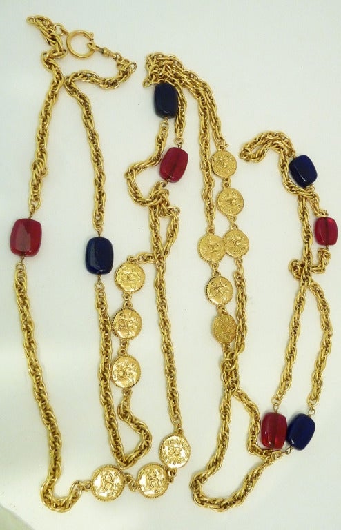 This vintage signed Chanel necklace features blue and red Gripoix glass with circular medallions bearing the CC logo and name, all in a gold-tone setting.  This piece measures 102 inches long with a spring closure, one rectangular Gripoix glass is