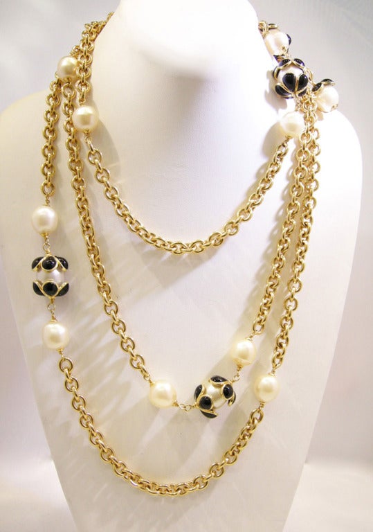 This vintage Chanel sautoir features faux pearls with black Gripoix glass camellia accents on either side of the faux pearls.  This Chanel sautoir measures 68 inches long and a single 7/8 inches x .75 inches with a spring closure and is in excellent