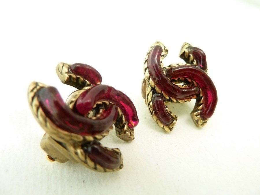 These vintage signed Chanel earrings feature cranberry color Gripoix glass in a gold-tone setting.  In excellent condition, these clip earrings measure 7/8 inches x 5/8 inches and are signed Chanel in block style.