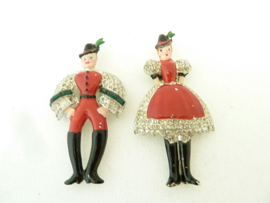 These fur clips are made with the same enameling technique and decorated in the red, green and black enameling with clear rhinestone accents in their native Bavarian costume. It is set in silver-tone setting. The woman measures 2 5/8 inches x 1 ¼