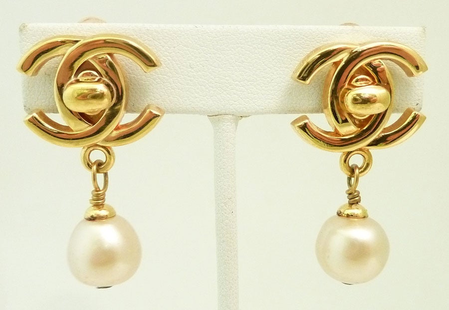 These vintage signed Chanel earrings feature the famous Chanel CC logo with faux pearl accents in a gold-tone setting.  In excellent condition, these clip earrings measure 1 ½ inches x 7/8 inches and are signed Chanel 96P Made in France.