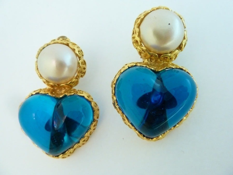 These vintage signed Chanel earrings feature striking blue Gripoix glass shaped in a floating heart, with cabochon cut faux pearl accents in a gold-tone setting. In excellent condition. these clip earrings measure 1 ¾” x 1 1/8” and are signed Chanel