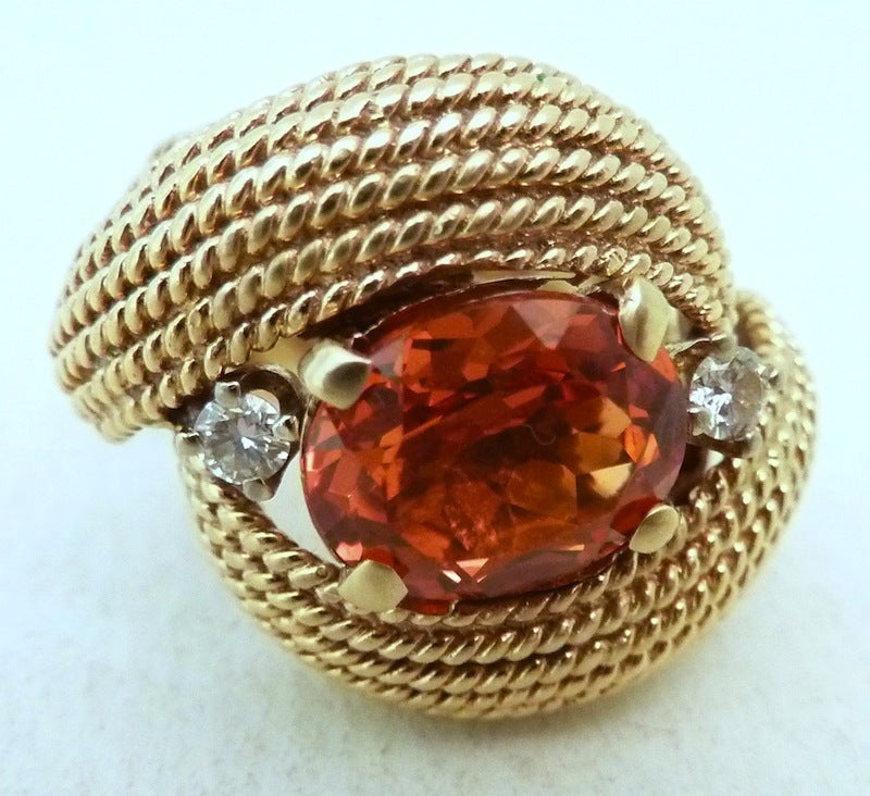 This vintage ring features a large bezel cut 3ct orange garnet stone with two 10pt diamonds in a 14kt gold setting.  This ring is a size 5, measures 3/4inch across the top and is in excellent condition.