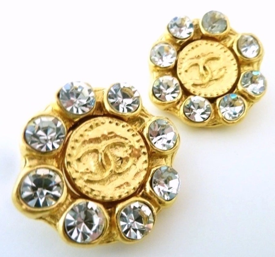 These vintage signed Chanel earrings feature the famous CC logo accented by bezel cut clear rhinestones in a gold-tone setting. In excellent condition, these clip earrings measure 1 ½” across and are signed Chanel Made in France.