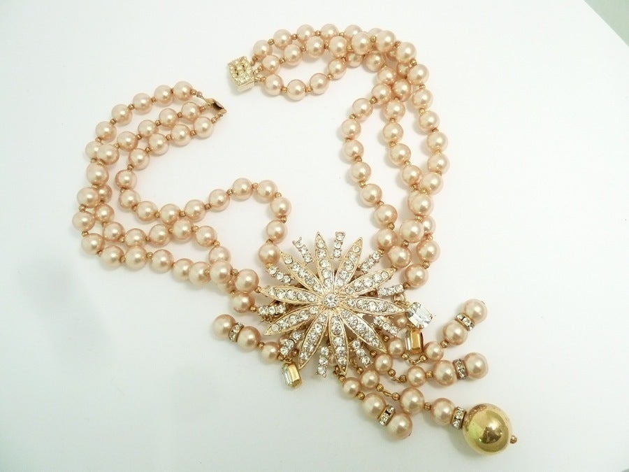 This vintage necklace features pink faux pearls with clear rhinestone accents in a gold-tone setting.  In excellent condition, this necklace measures 17” long with a pressure closure; the centerpiece pendant is 2 ½” wide x 5 ¼” long.