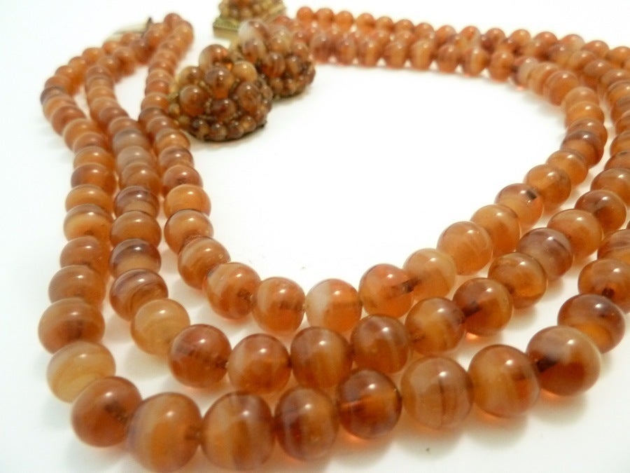 This vintage signed Coppola e Toppo Italy set features dark coral color glass beads in a gold-tone setting.  The necklace measures 15 ½” with a pressure closure and each bead is ¼” in diameter; the clip earrings are 1 1/8” x 1”.  In excellent