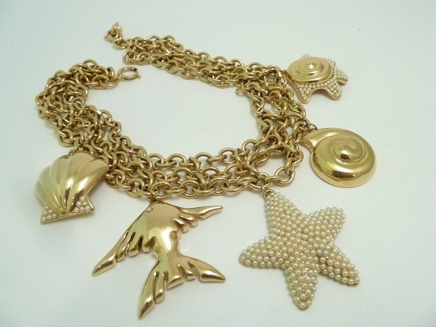 This vintage signed Guy Laroche necklace features a seashell design with fish, starfish and seashell charms with faux pearl accents on a gold-tone setting. In excellent condition, this necklace measures 16 ½” and the center starfish charm is 1 ¾” in