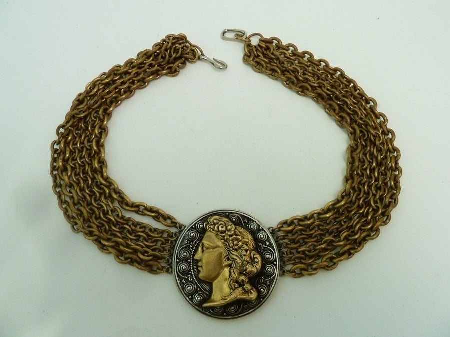 This vintage signed La Porte Bleue Paris necklace features a large Roman God centerpiece with 6 strands of link chain on a gold-tone setting. The centerpiece measures 2” in diameter and the necklace is 17” with a pressure closure. The necklace is in