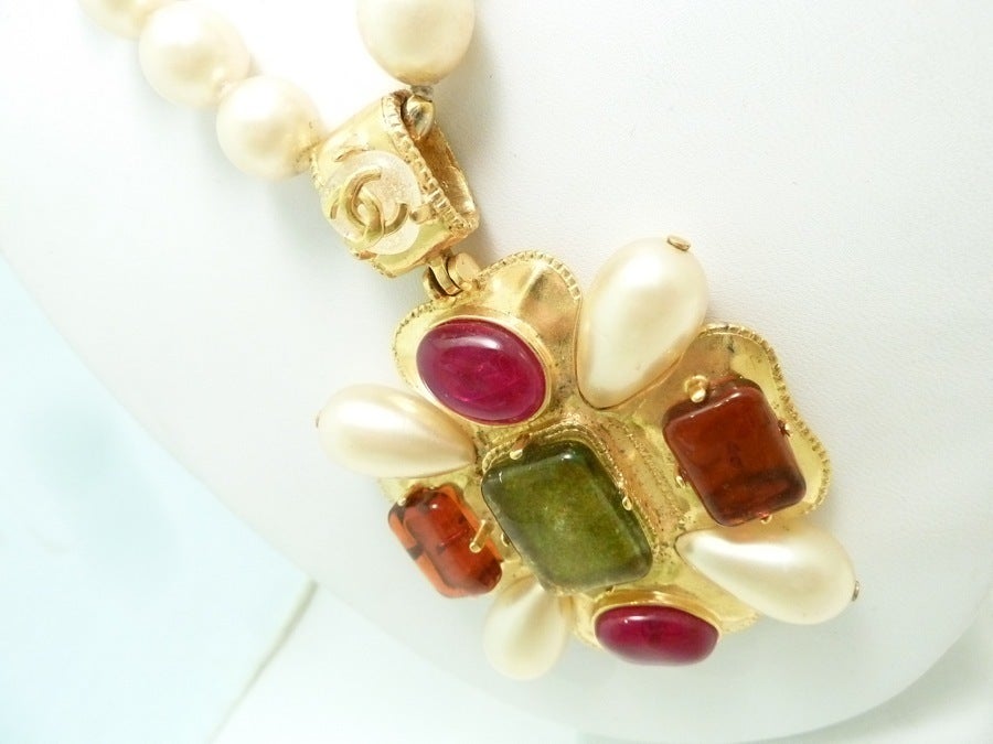 This vintage signed Chanel necklace pendant with green and red Gripoix glass and white faux pearls in a gold-tone setting.  The pendant measures 3 ¼” x 2 ¼”; the necklace is 19” x ½” with a hook closure.  In excellent condition this pendant necklace
