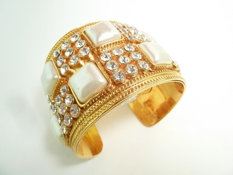 This vintage very wide signed Chanel cuff bracelet features faux pearls and clear rhinestones in a gold-tone setting. In excellent condition, this bracelet measures 7 ½” x 2” and is signed Chanel Made in France.
