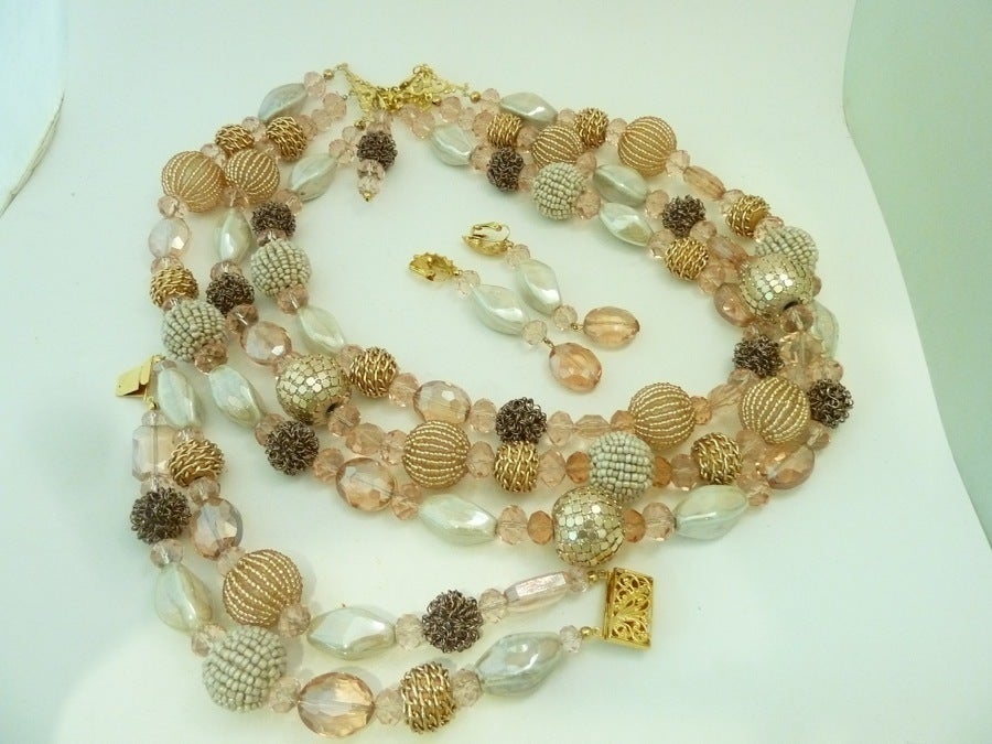 This signed R. E. Roselli set features multi-textured pink-toned beads in a gold-tone setting.  The 3-strand necklace measures 24” with a spring closure and the largest bead is 7/8”. The bracelet is 8 ¾” x 1 ¼” with a pressure closure and the clip
