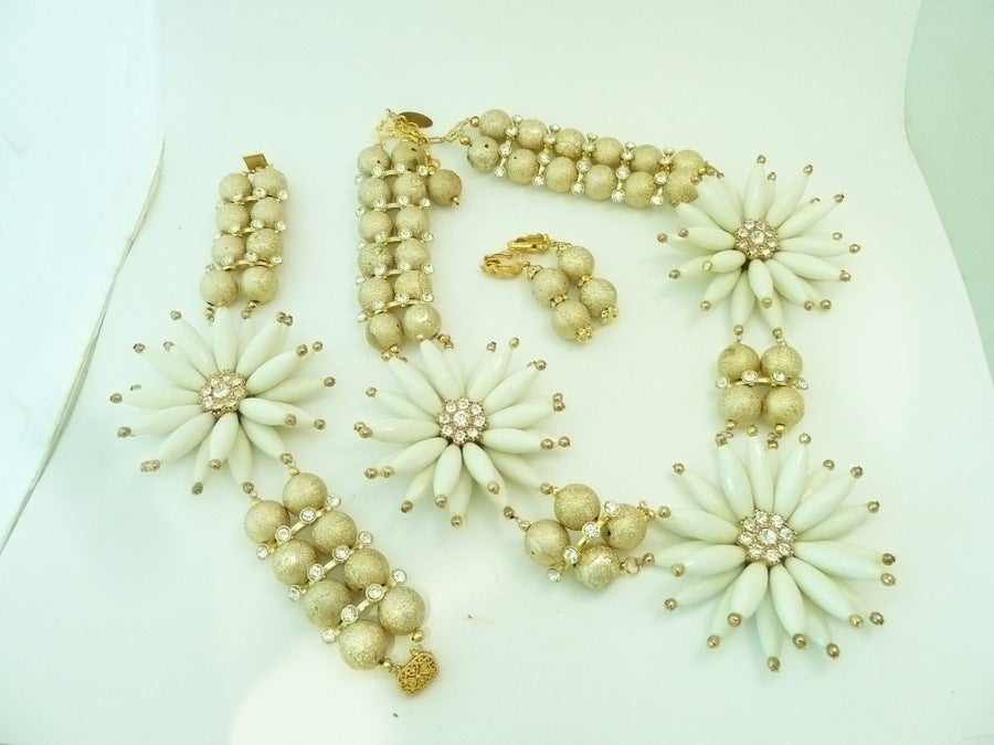 This signed one of a kind R.E. Roselli set features large ivory color Lucite floral designs with clear rhinestone accents and textured gold-tone balls.  The necklace measures 25” and the center drop floral design is 3” across with a spring closure. 