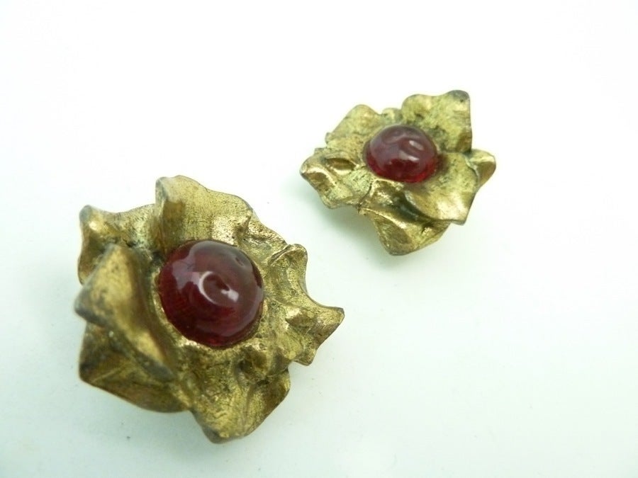 These vintage signed Chanel earrings feature red Gripoix glass with heavily etched leaves in a gold-tone setting. In excellent condition, these clip earrings measure 1 ¼” and are signed Chanel 1981.