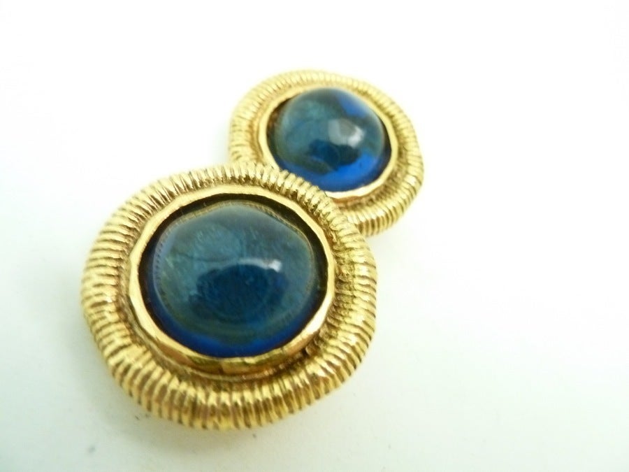 These vintage signed Chanel earrings feature blue cabochon Gripoix glass stones in a gold-tone setting. In excellent condition, these clip earrings measure 1 1/8” in diameter and are signed Chanel Made in France.