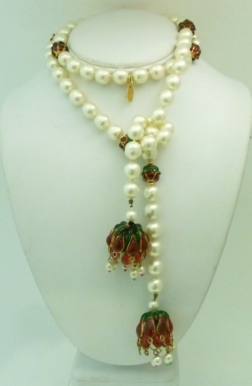 This vintage 1970’s signed Chanel necklace features a versatile lariat design with incredible red and green Gripoix glass and white faux pearls in a gold-tone setting. This piece measures 36” long; each end is 1” in diameter and each faux pearl is