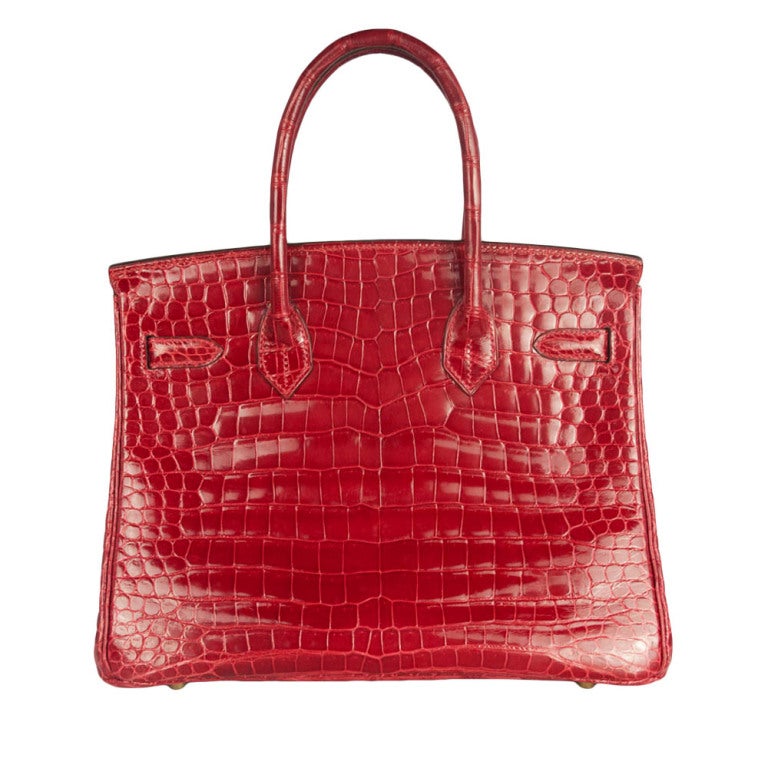 This is a red 30 cm Birkin bag made with Porosus Crocodile skin – commonly found on the northern shores of Australia. There is no glaze overlay, which means this bag will never peel. Instead the bag is polished with an agate stone before being hand