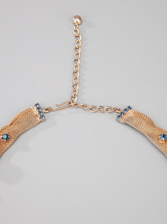 Gold 1960's 'Hobe' mesh necklace featuring blue and green rhinestone detailing and a series of dangling chains with stone adornments. 

Measurements: Pendant: 13cm, Circumference: 50cm

Returns Policy: Final Sale - No Returns.

All of our