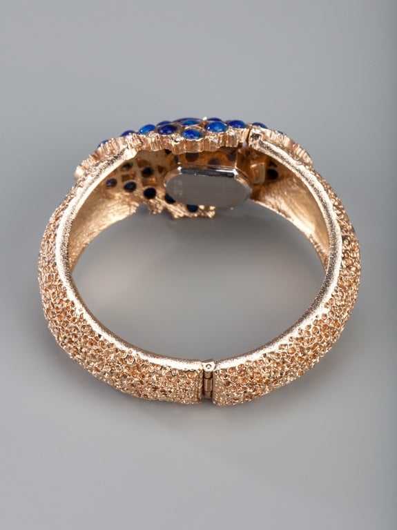 Gold-tone cuff featuring blue cabochons and diamante accents. A watch is hidden beneath the embellished vintage stone front.