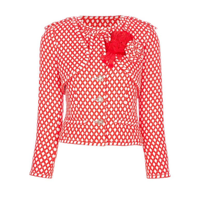 Red and white cotton and silk blend suit from Chanel featuring a long sleeved jacket with a round neckline, a button down front fastening, front pockets, a diamond check print and a bow and corsage detail at the top. The skirt features a mid rise,