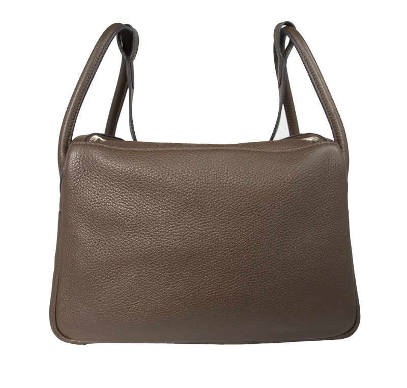 This brown Hermes Lindy bag is made from soft luxurious Clemence leather. The box shape means this bag is highly practical and the double zip opening allows for easy access to your belongings.  The bag is fastened with the classic Hermes turn lock