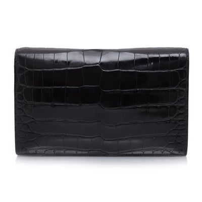 This 'Annie' Clutch by Hermes is crafted in crocodile leather and accented with gold hardware. This piece boasts a front pocket plus a zip pocket and an open pocket in the interior, which is fully lined in supple black leather. This piece features