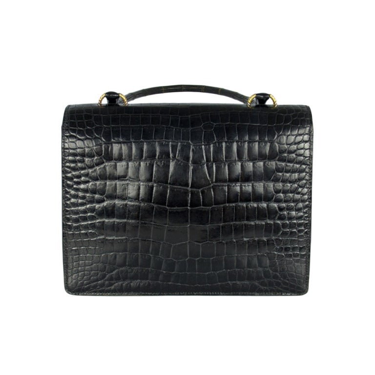 Hermes crocodile 'Vasco' bag featuring gilt metal hardware and matching rolled handles. Inside the bag holds two compartments, one pocket and two open sleeves. Inside the Hermes logo is embossed in gold. 

Colour: Black, gold hardware

Material:
