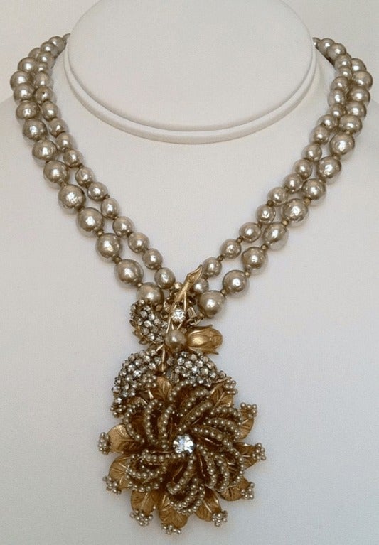 Fine vintage Miriam Haskell pendant necklace. Exquisite signed double strand baroque 'pearl' necklace features an elaborate floral pendant. Gilt metal drop features a Swarovski center and encrusted faux seed pearl 'petals'. Original hidden push