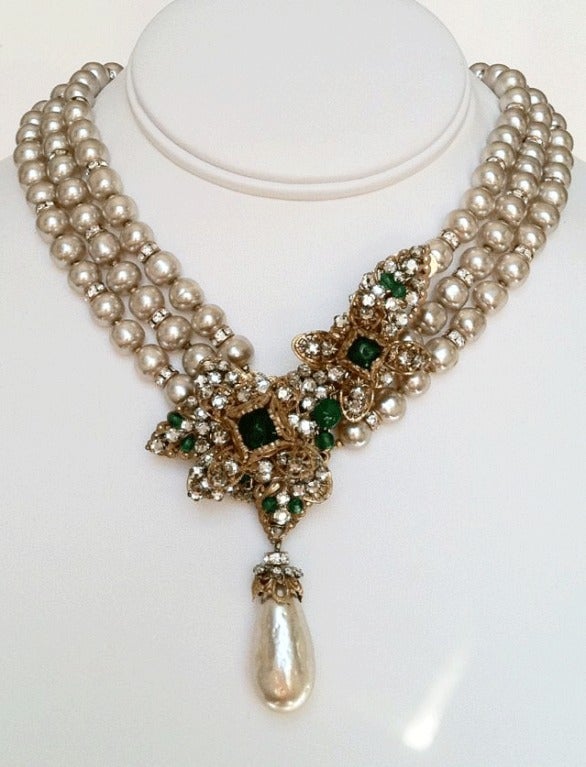Rare vintage Miriam Haskell prototype pendant necklace. Signed gilt metal item features three strands of faux baroque pearls/crystal spacers. Exquisite gilt metal floral pendant trimmed with Swarovski crystals, green pate de verre glass center and