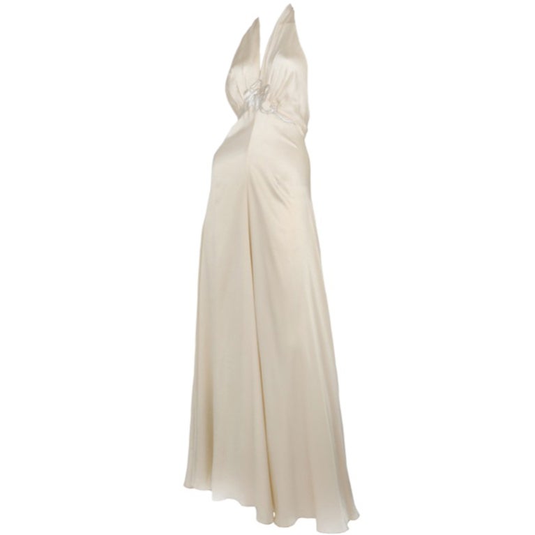 White satin halter gown with ribbon appliqué at bust and hook and eye closure at back.