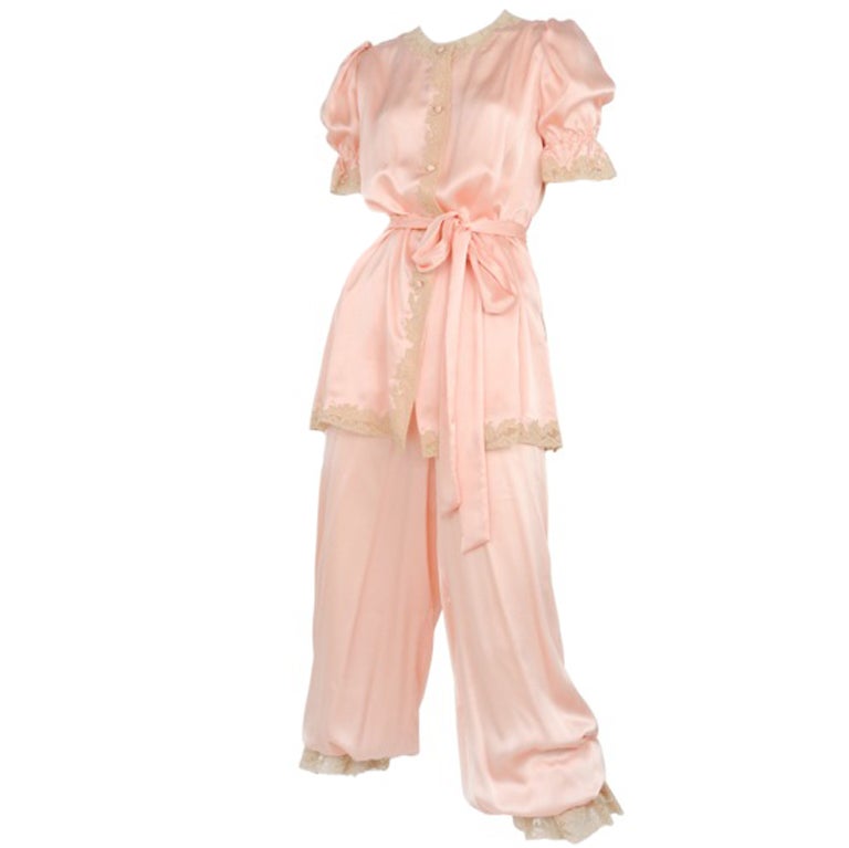 Pink satin pajama set with cream lace detail and button up top with waist tie closure.