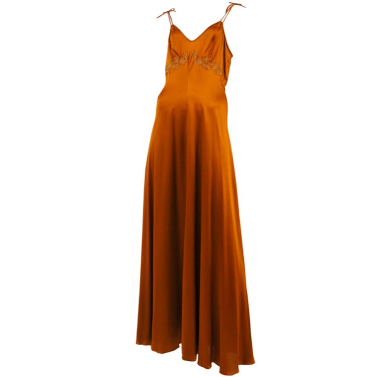 Copper silk satin gown with leaf appliques at waist and thin double shoulder straps with bow detail.