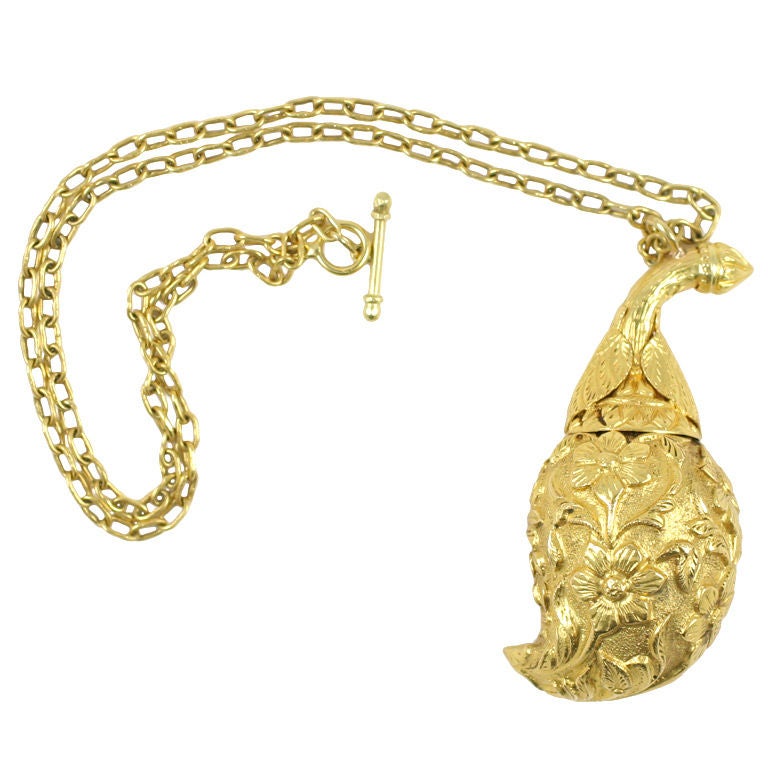 An 18kt yellow gold make-up pendant. The pendant is fashioned in the shape of a gourd and is adorned with flowers and vines. The stem of the gourd unscrews and reveals a gold sharp wand. The wand would have been used to apply eyeliner. The pendant