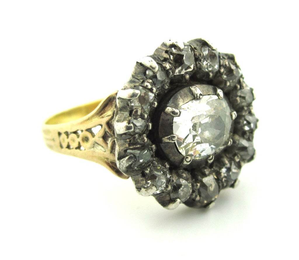 Composed of 18 karat yellow gold & silver topped. Centering a very early Old Mine Cut diamond with a surround of smaller Old Mine Cut diamonds, collet set in a closed foil backed setting. The shank is enhanced by a delicate pierced open work