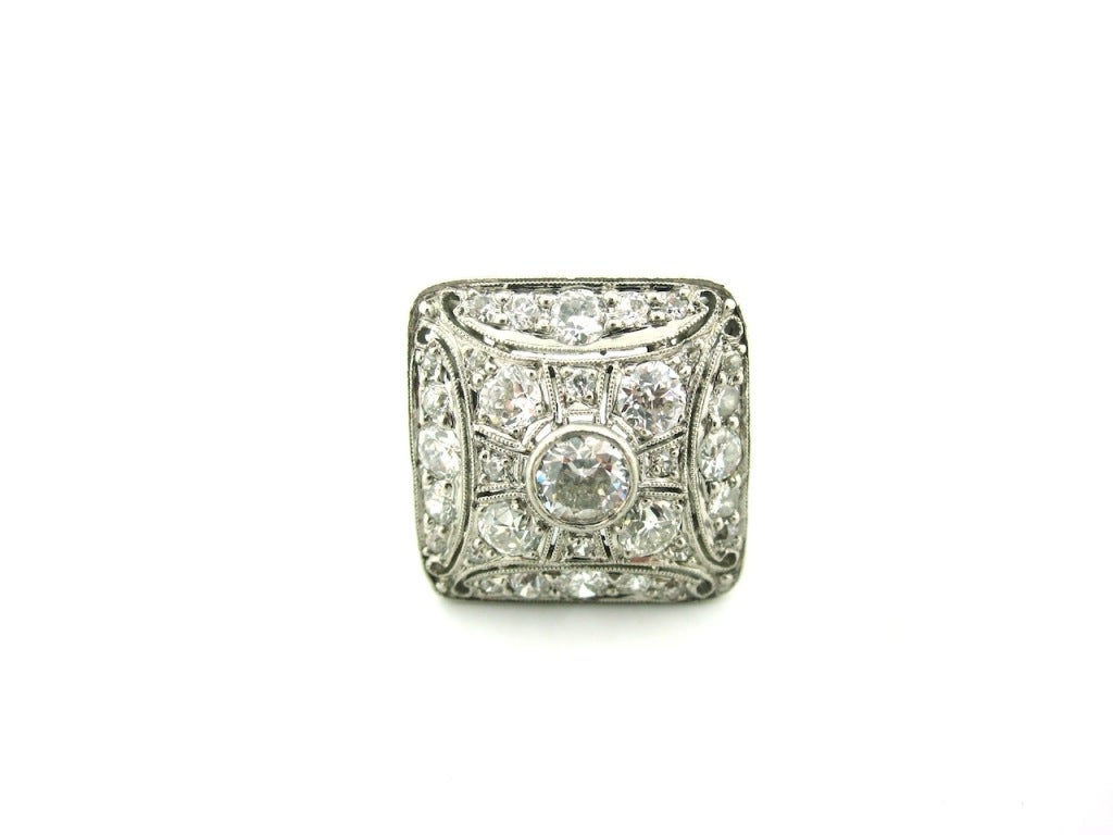 Art Deco era platinum & diamond ring in a square geometric form with an intricate pierced open work & filigree design. The shank of the ring is elaborately hand engraved. Set with 37 Old European Cut diamonds weighing 1.96 Carats in total. 33