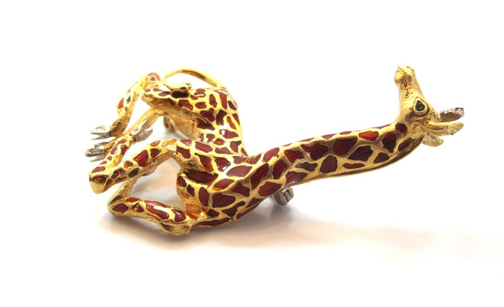 A unique & realistic giraffe motif brooch by Tiffany & Co. from the 1960's. Composed of solid 18 karat yellow gold, brown enamel, green emerald set eyes, round diamonds set in the ears and baguette cut diamonds set in the feet. Weighing 26.8 Grams.