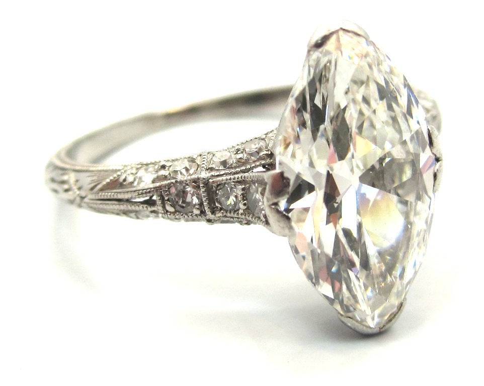 Exquisite handcrafted carved & pierced platinum Edwardian era (Circa 1915) engagement ring featuring a center stone 2.43 Carat Antique Marquise Cut diamond. Prong set in the center of the mounting that is accented with 22 smaller Old Single Cut