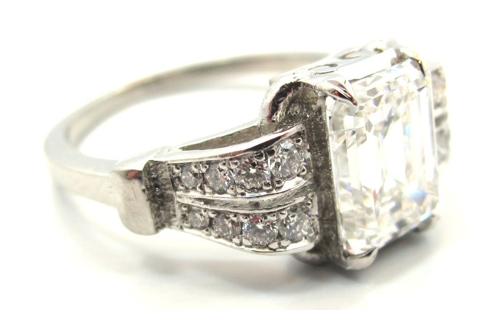 Unusual Art Deco era engagement ring (circa 1935). Handcrafted and composed of solid platinum. Featuring a 2.05 Carat Emerald Cut Diamond (Rectangular Step Cut) accompanied by a GIA Diamond Grading Report stating that the stone is E in color & VVS2