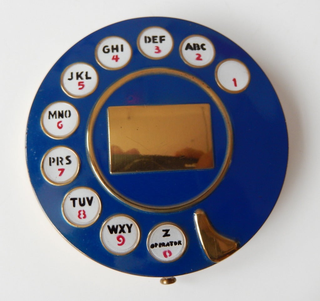 A fifties ladies compact in the shape of a rotary telephone dial that was inspired by a similar compact designed in 1935 by Salvador Dali for Schiaparelli. It has it's original filter and powder puff and there is an area on the dial for engraving.