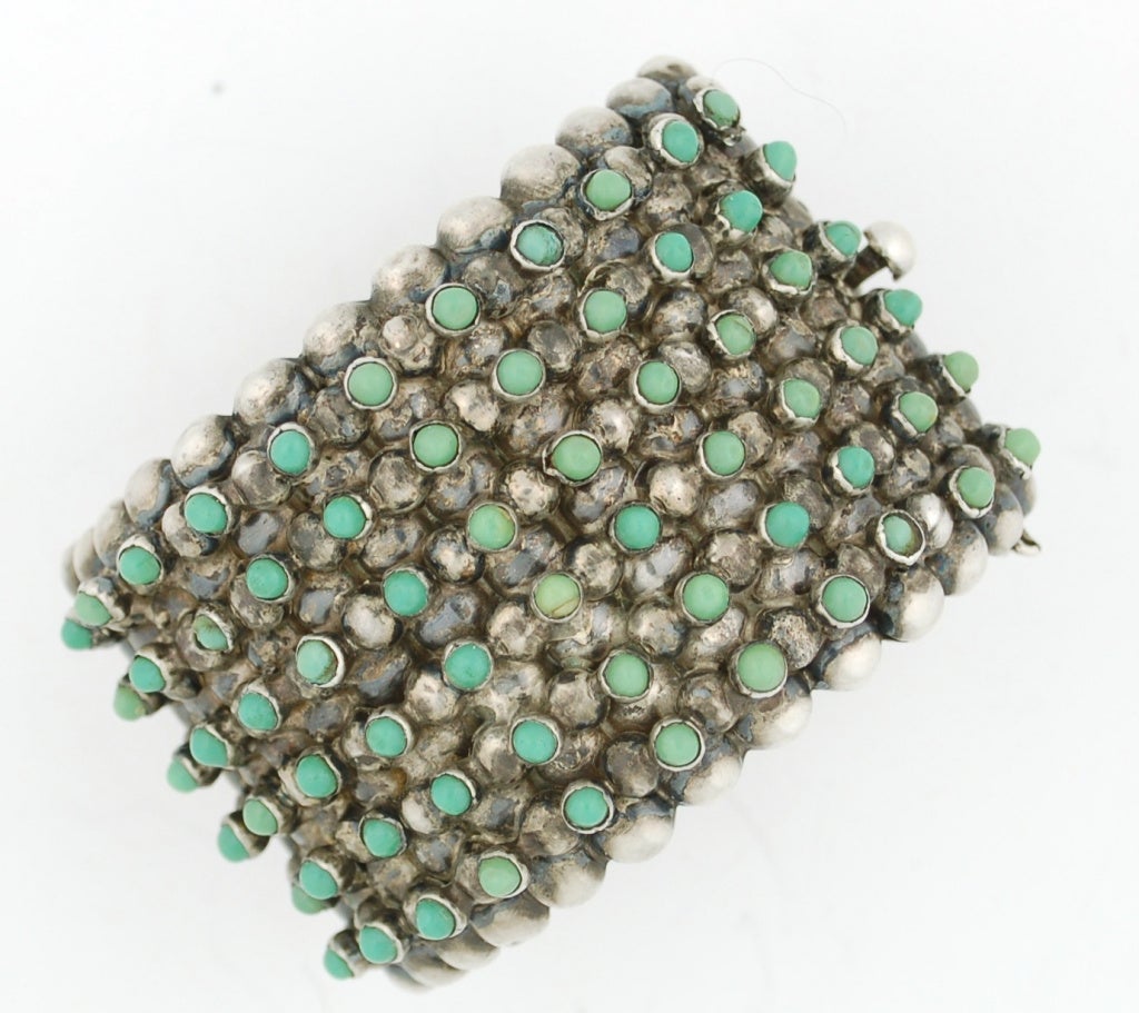 This is a fabulous two inch wide bracelet.  Adorned with rows of green-blue turquoise.  The style was combo in Mexico in the early 20th C.  This bracelet is really monumental and delicate at the same time.  The turquoises are only present on the