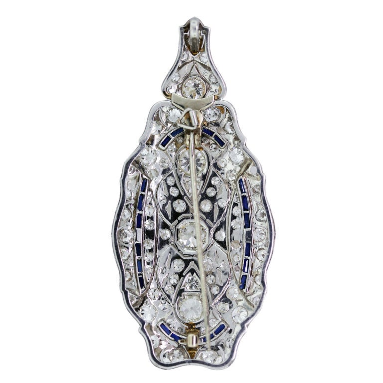 This Vintage Diamond and Sapphire Pin/Pendant is Set in Platinum Material. It has Approximately 5Ctw of Diamonds. The Diamond Clarity is VS and H/I in Color. The Accents are Blue Sapphires. The Dimensions of this Pin/Pendant is 2 5/8
