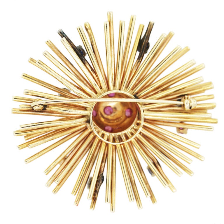 This 14k Yellow Gold Pin has 9 Rubies and 4 sapphires mounted on a radial style celestial themed setting. The pin is 2