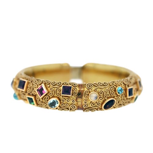 This 18k Yellow Gold Bangle has 10 different multi-colored gemstones. Moonstone, Citrine, Turquoise, Amethyst, Rhodolite Garnet, Black Opal, Almandine Garnet, Pink Tourmaline, Green Tourmaline and Aquamarine. Some of the Stones are Chipped, but