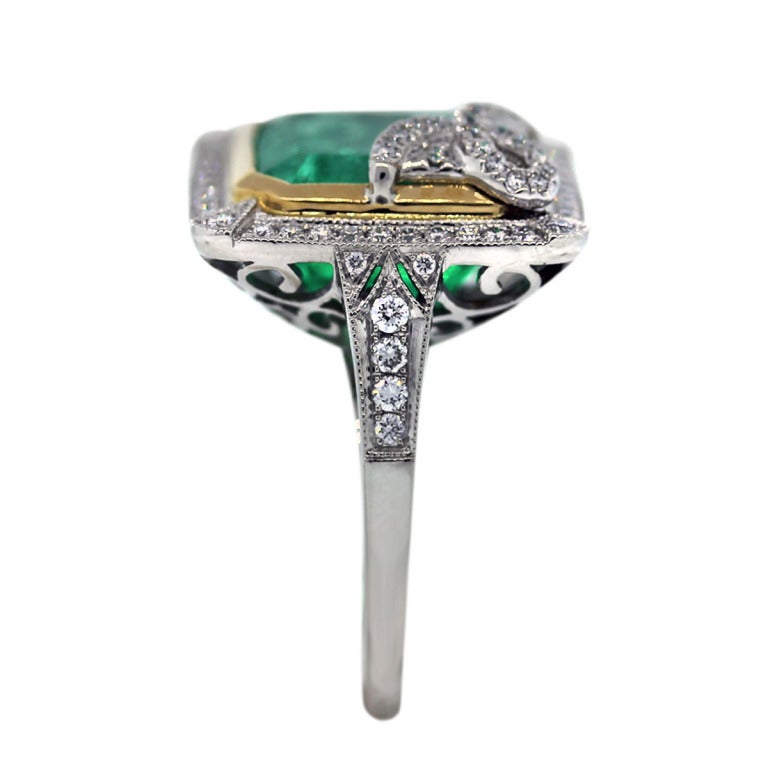 This Vintage Style Platinum and Gold Cocktail Ring features a huge 8.65ct Square Cut Green Emerald measuring 12mm x 11mm. The stone is set in a Platinum and 18k Yellow Gold band sized at 6.5 (sizable). There are 0.43ctw of Diamonds. The Diamonds are