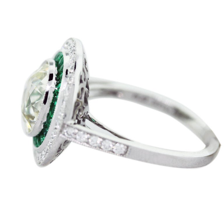 3 Carat Diamond, Platinum and Emerald Vintage Style Engagement Ring, Center Diamond is 3.01ct L/M in Color VS in Clarity. Accent Diamonds are 0.36ctw H/I in Color and VS in Clarity. Emeralds are 0.85 ctw Size 6.5