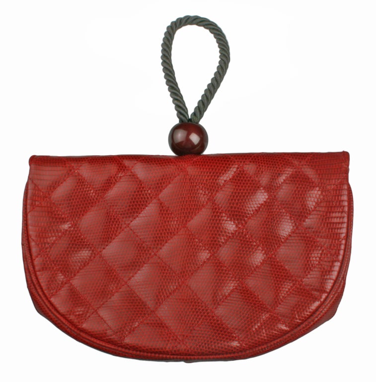 This Asian inspired bag is a beautiful cinnabar red.  It can be held as a clutch or looped on your wrist. The bag has one interior zippered pocket and a snap closure. Marked CHANEL and made in Italy.