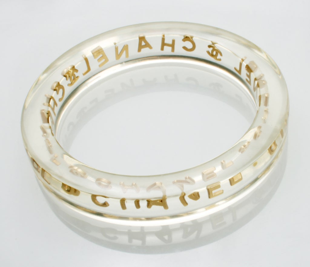 This CHANEL bangle bracelet has individual metal pieces suspended in lucite. The inside diameter is 2 1/2 